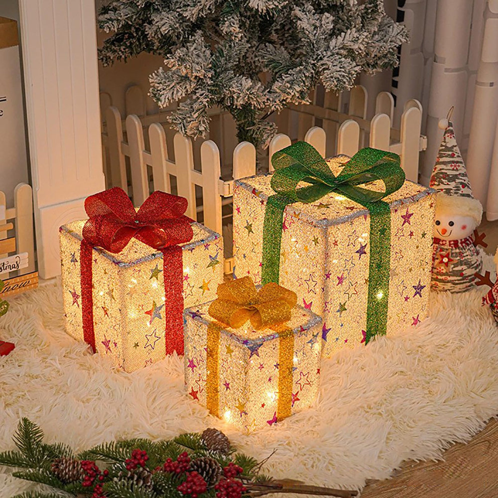 Lighted gift boxes set of 3 glowing on a snowy porch at Christmas