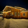 Outdoor curtain lights hanging warm white along a house roofline - photo 2