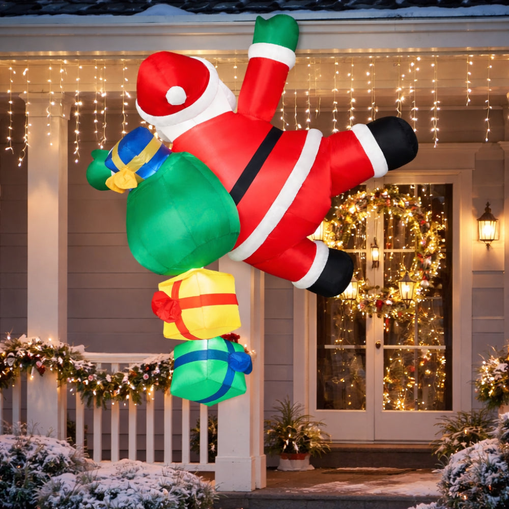 Christmas inflatable climbing Santa lit up on a house at night