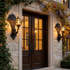 Two peacock wall sconces flanking a grand front entrance in the evening