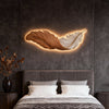LED wall art feather wall light, hung horizontally above a bed
