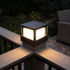 Outdoor post cap light on a composite deck rail newel post casting a warm pool of light