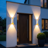 Pair of black up and down outdoor wall lights either side of a front door casting overlapping beams at dusk