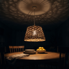 Wide 15 inch rattan pendant light lit above a round dining table at night