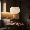 White silk drum chandelier lit neutral 4500K above a kitchen dining nook at golden hour