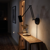 Compact black swing arm wall sconce over a hallway console table at night