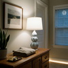 Gray-blue gourd ceramic lamp glowing on an oak dresser at night