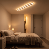 White slim linear LED ceiling bar flush mounted in a warm bedroom at 3000K