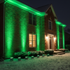 Green holiday flood light wash on a brick house with snow