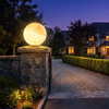 12 inch solar moon sphere post light glowing on a stone gate pillar at dusk