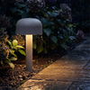 Mushroom pathway light glowing in the rain beside a garden path