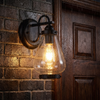 Vintage clear glass wall lantern glowing beside a front door in the rain