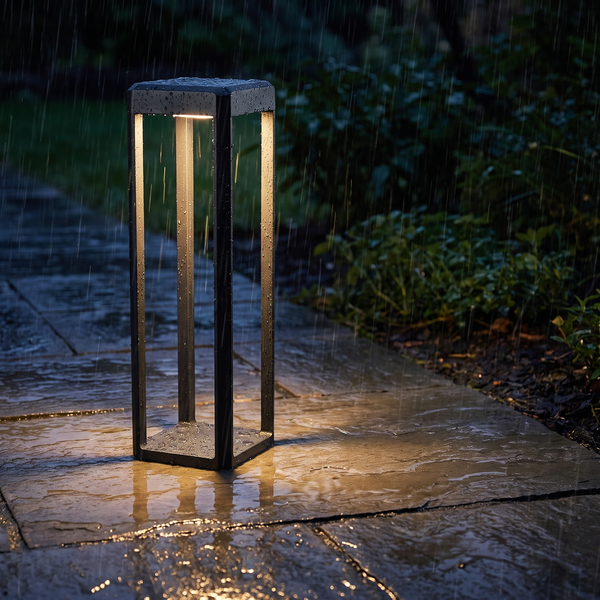 Modern black pathway light beside a slate walkway in steady rain