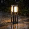 Garden bollard light glowing through heavy rain on a stone path