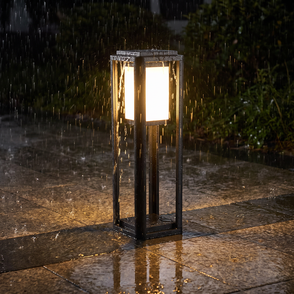 Garden bollard light glowing through heavy rain on a stone path