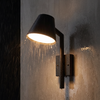 Black cone wall sconce shedding rain with a warm downlight at night
