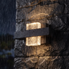 Crystal up down wall light glowing on wet stone in night rain