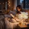 Woman reading in bed beside the glowing feather night light