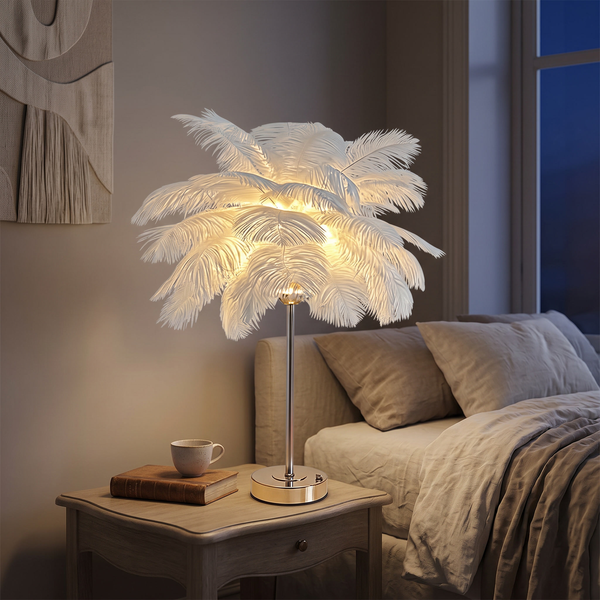 White ostrich feather table lamp glowing on an elegant bedside table