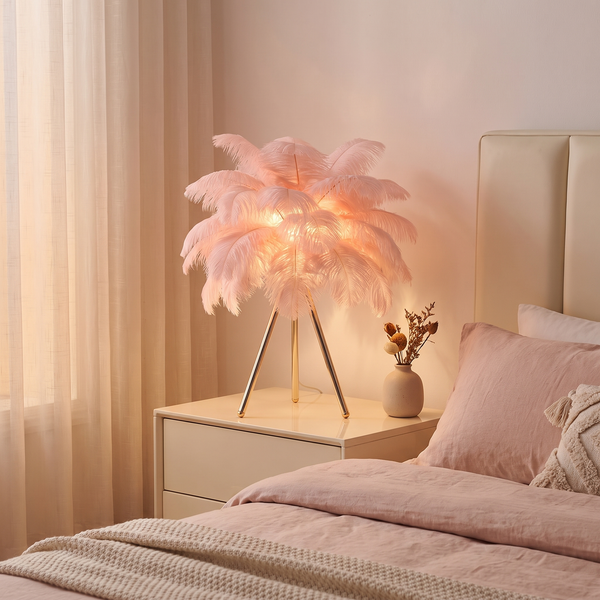 Pink feather tripod table lamp glowing softly on a bedroom nightstand