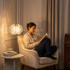 Woman reading in a cream armchair beneath the crystal petal pendant