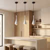 Three white cone pendant lights hanging in a row over a modern kitchen island