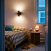 Two-tone up down wall sconce beside a bed