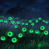 Green solar eyeball stake lights glowing in a dark garden