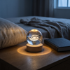 Crystal ball night light glowing on a bedroom nightstand, Milky Way galaxy engraved inside