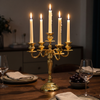 Black metal candelabra with lit taper candles on a console table in a dim entryway