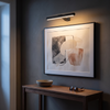 Black cordless picture light 15.7 inch lit above framed art in a modern entryway