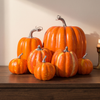 Set of seven orange decorative foam pumpkins on a walnut console in warm afternoon light