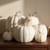 Set of seven white decorative foam pumpkins on a walnut console in warm afternoon light