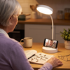 Cordless gooseneck desk lamp lighting a crossword with a phone video call in the base slot