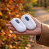 White magnetic rechargeable hand warmers held in one palm on an autumn walk