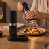 Electric salt and pepper grinder seasoning a plate with LED light on