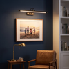 Black picture light above a framed family beach photo in a navy home study