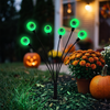 Close-up of a green solar eyeball stake light in a Halloween flower bed