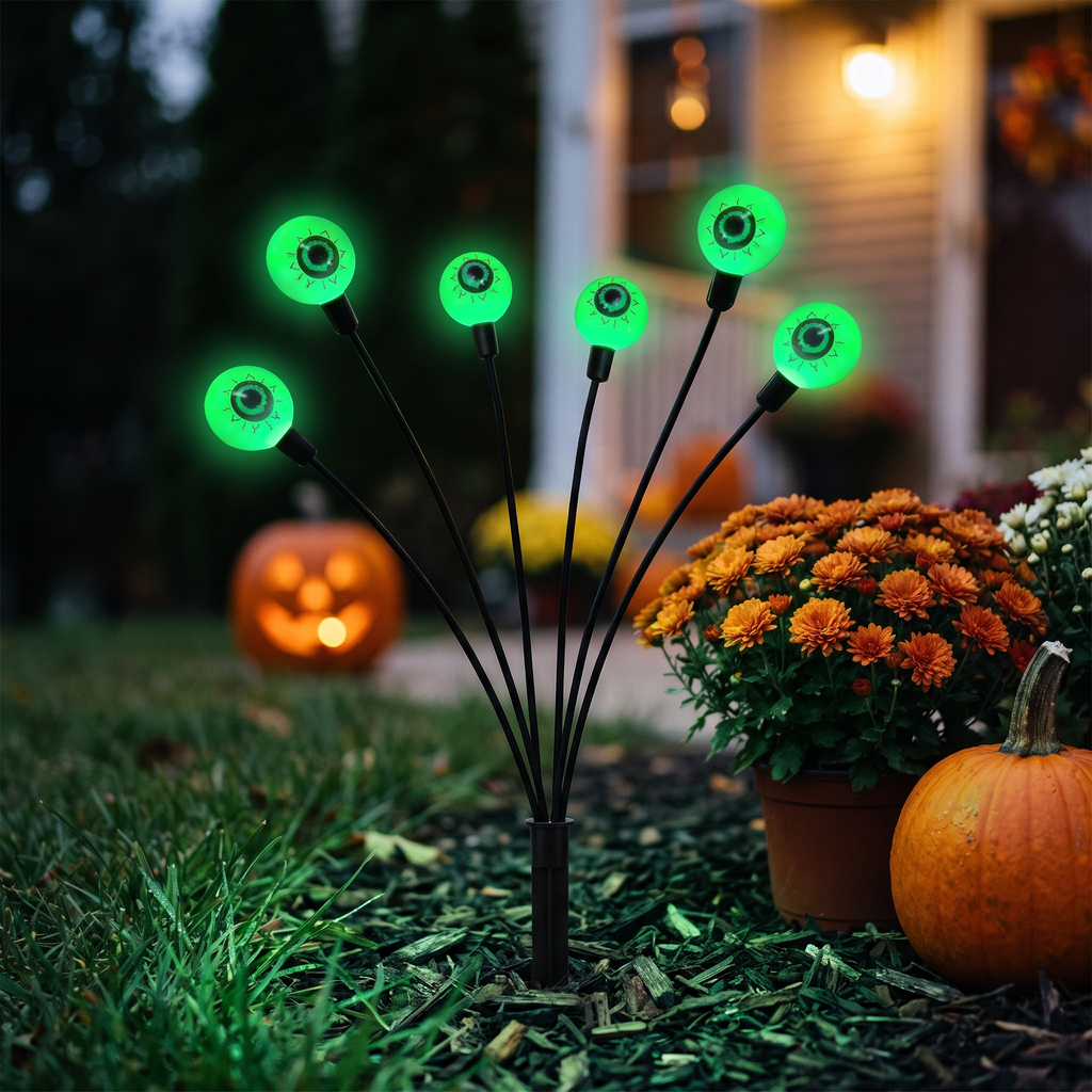 Close-up of a green solar eyeball stake light in a Halloween flower bed