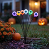 Close-up of a multicolor solar eyeball stake light in a Halloween flower bed