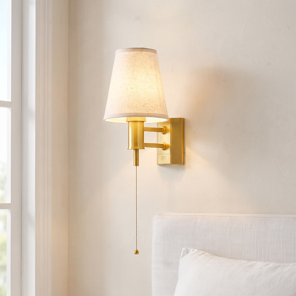 Battery wall lamp with fabric shade, gold, beside a bed