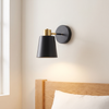 Cordless cone wall sconce, black and gold, rechargeable with remote, beside a bed