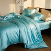 Silk bedding set on an unmade bed, Blue