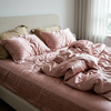Silk bedding set on an unmade bed, Pink
