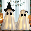 Two white ghost figures with witch hat and bow glowing on a table