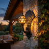 Peacock wall sconce on a covered front porch column at dusk