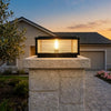 Square solar pillar light on a tall stone driveway-entrance pillar in the evening