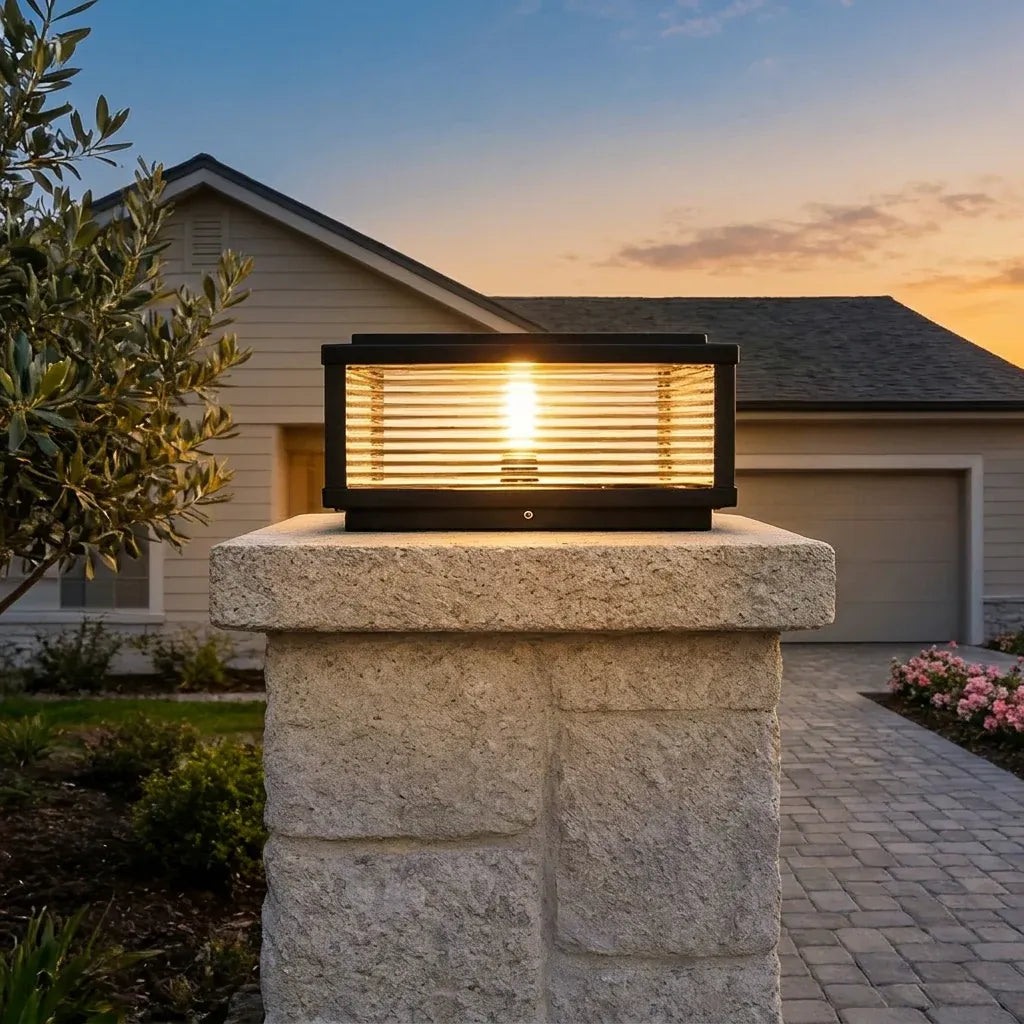 Square solar pillar light on a tall stone driveway-entrance pillar in the evening