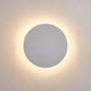 Round wall sconce lit in a modern staircase