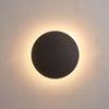 Round LED wall light beside a bed
